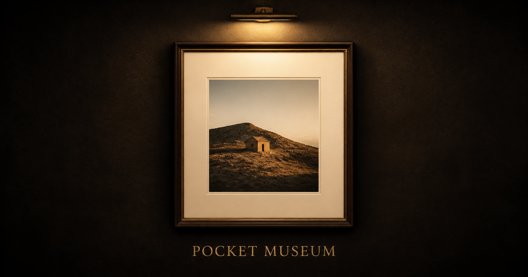 A landscape photograph framed beneath a gallery lamp